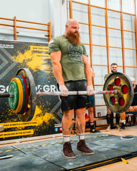 Man lifting a barbell in a gym setting with a visible 'Grip' brand banner.